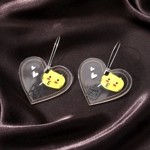 Detail of cute acrylic heart earrings featuring cat and milk carton designs on silk
