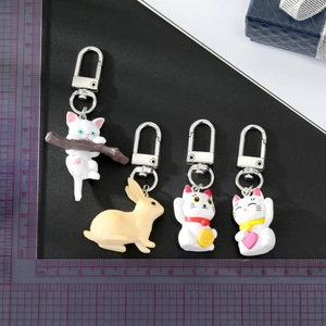 Cute cartoon cat and rabbit resin keychains with silver lobster clasps on a scale mat