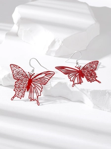 Artistic red butterfly hollow earrings with floral patterns on white stone display