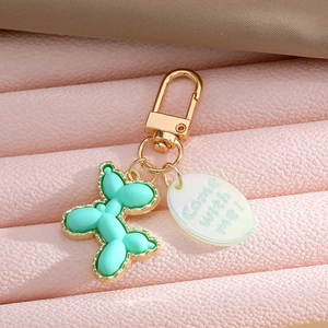 Detailed close-up of mint green resin balloon dog keychain with golden metal trim