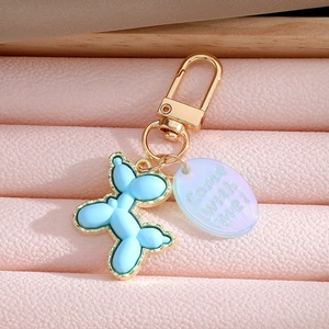 Blue balloon dog keychain with gold edges and translucent tag on pink leather background