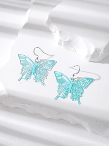 Close-up of light blue hollow butterfly earrings on a white textured stone surface