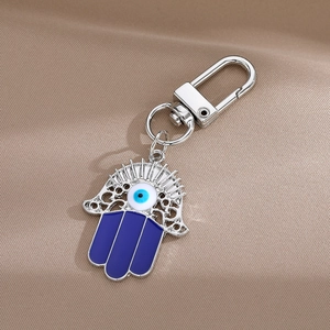 Détail du porte-clés Main de Fatma avec œil bleu sur fond de tissu soyeux