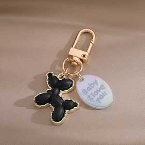 Detailed macro of a black resin balloon dog keychain with golden alloy edges and charm