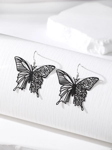 Detail of matte black butterfly earrings with intricate cutout floral and line patterns