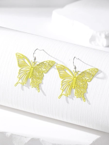 Detailed macro shot of yellow hollow butterfly earrings with floral patterns on white pedestal