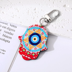 Detail eines Hamsa-Hand-Schlüsselanhängers mit Nazar-Auge auf weißem Steinboden