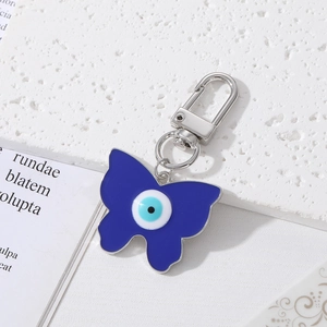 Porte-clés papillon bleu avec œil maléfique en émail sur fond de marbre élégant