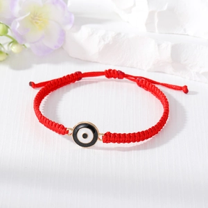 Detail of red woven Evil Eye bracelet with golden metal trim and adjustable clasp