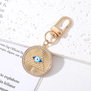 Detail of gold keychain with Eye of Providence pendant and sparkling crystal border