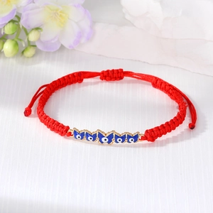 Close-up of red woven bracelet featuring blue butterfly evil eye charms and pull string