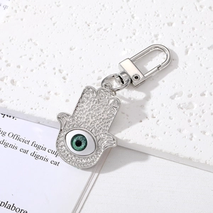 Detailed macro view of silver Hamsa Hand keychain with green Evil Eye and intricate filigree