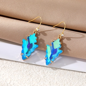 Macro detail of geometric teardrop earrings with gradient blue crystals and gold hooks