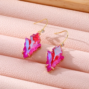 Macro shot of geometric magenta leaf-shaped crystal earrings with gold ear hooks