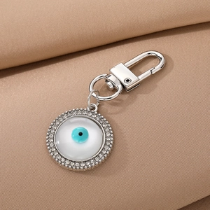 Turkish Evil Eye keychain with round crystal rhinestone pendant on brown fabric background