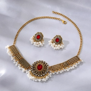Detail einer goldenen Vintage-Kette mit roten Steinen und weißen Perlen auf Seide