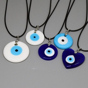 Détail de pendentifs mauvais oeil en verre coloré de formes rondes et coeur sur cordons