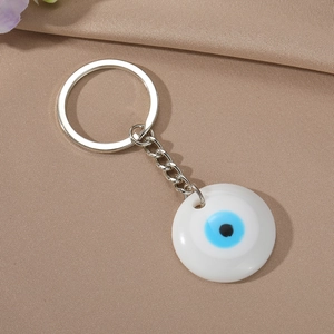 Detail of the blue resin Evil Eye pendant with polished silver key ring on satin