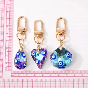 Blue crystal Evil Eye keychains in heart and shell shapes with gold-plated lobster clasps