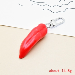 Detail of creative red chili resin keychain with metal clip on light background