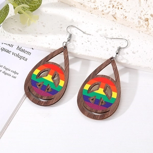 Detail of wooden teardrop earrings featuring a rainbow peace sign and smiley cutouts
