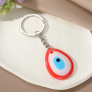 Detailed close-up of a teardrop-shaped Turkish Evil Eye keychain on a white plate