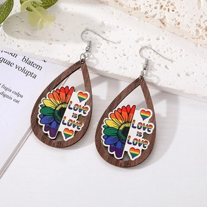 Detail of wooden teardrop earrings with Love is Love rainbow print on white stone surface