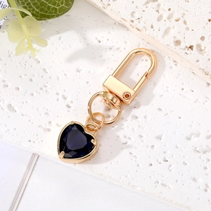 Elegant gold keychain featuring a faceted deep blue heart crystal on a stone surface