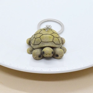 Three-headed turtle keychain with vintage green resin texture on a white plate