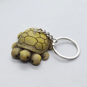 Unique three-headed turtle keychain with wood texture finish on a clean grey background