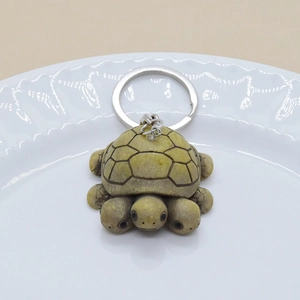 Creative three-headed turtle keychain with moss green resin texture on a white plate