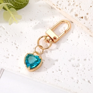Close-up of heart-shaped keychain with light blue crystal and golden D-ring clasp