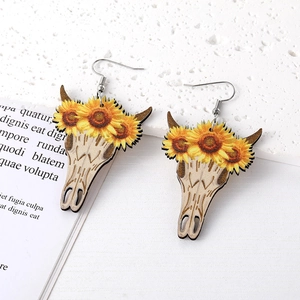 Dettagli di orecchini stile western con teschio di mucca e girasole su pietra