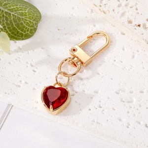Detailed macro view of the gold-tone heart-shaped red crystal keychain on a stone base