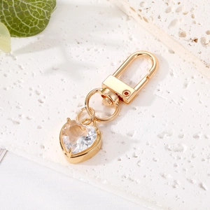 Macro detail of a heart-shaped crystal keychain with gold-plated metal clasp and claw setting