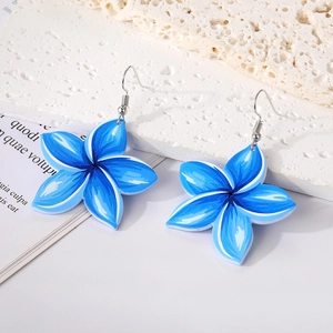 Blue acrylic flower earrings with silver hooks on white stone and paper backdrop