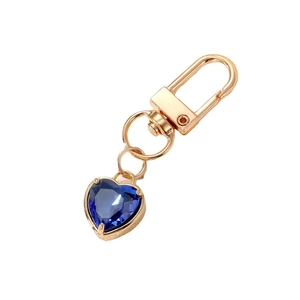 Elegant gold keychain with a multifaceted deep blue heart-shaped crystal pendant for bags