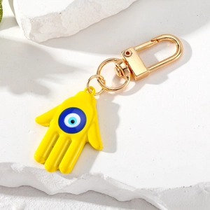 Detalle del llavero mano de Fátima amarillo con ojo azul sobre un fondo de piedra texturizada