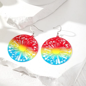 Detail der Regenbogen-Löwenzahn-Ohrringe, präsentiert auf weißem, texturiertem Stein