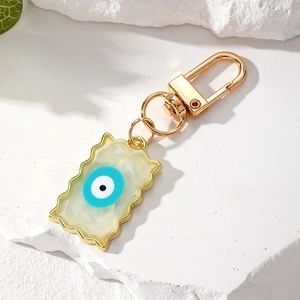 Macro shot of wavy resin pendant with gold evil eye charm and marble texture