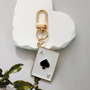 Creative Ace of Spades poker keychain with gold lobster clasp on white marble decor