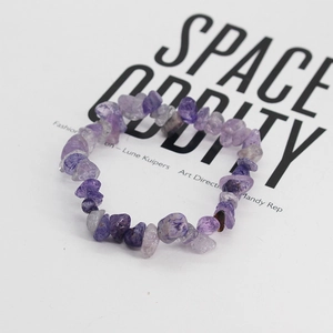 Dettaglio macro di perline di pietra naturale viola irregolari su bracciale elastico