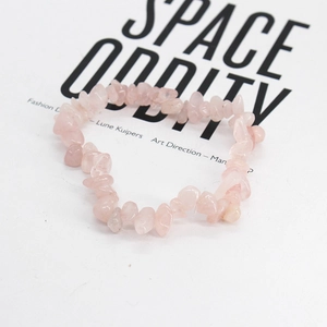 Dettaglio del bracciale in quarzo rosa naturale elastico su uno sfondo minimalista