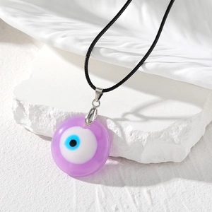 Gros plan du pendentif œil protecteur en résine violette avec motif bleu et cordon noir
