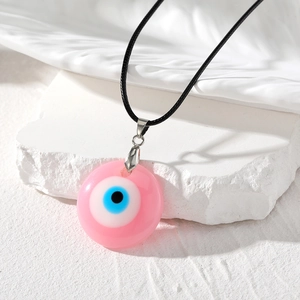 Détail macro du pendentif œil grec de style bohème avec base en résine rose et cordon noir