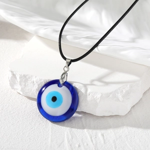 Détail du pendentif œil grec en résine bleue sur pierre blanche avec cordon noir tressé