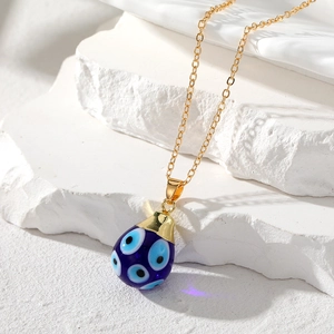 Detailed macro view of bohemian evil eye teardrop pendant with gold stainless steel chain