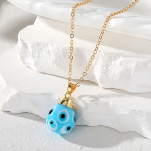 Vintage gold chain necklace with a teardrop blue evil eye glass pendant on white stone