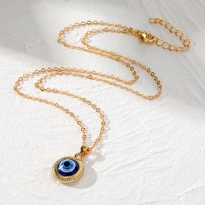 Collier rétro avec pendentif Evil Eye rond doré sur un fond texturé blanc épuré