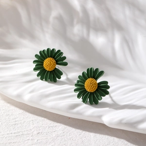 Matte dunkelgrüne Gänseblümchen Ohrstecker mit gelber Mitte auf weißem Keramiktablett